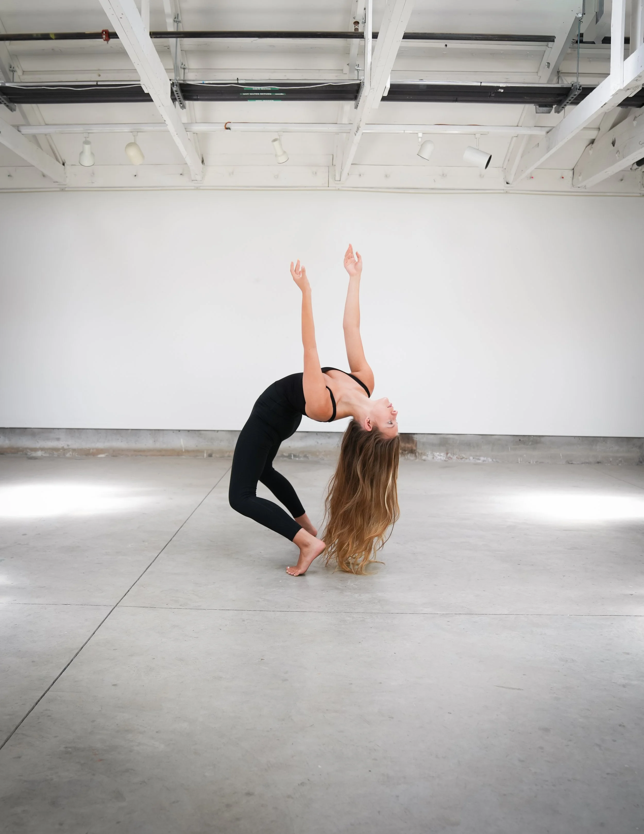 A TWDCC dancer in a contemporary backbend, studio floor.