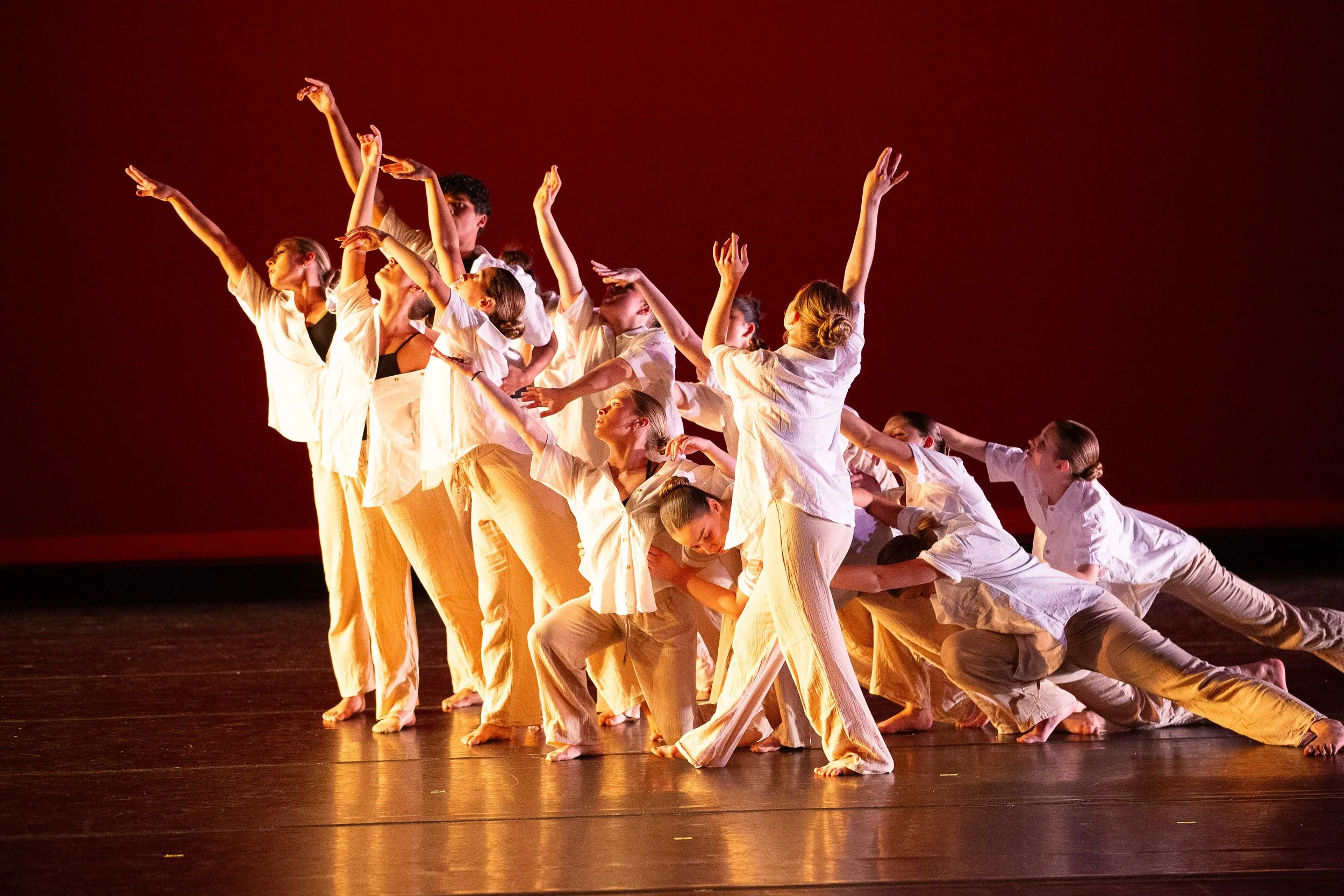Dancers performing contemporary choreography under red stage light.