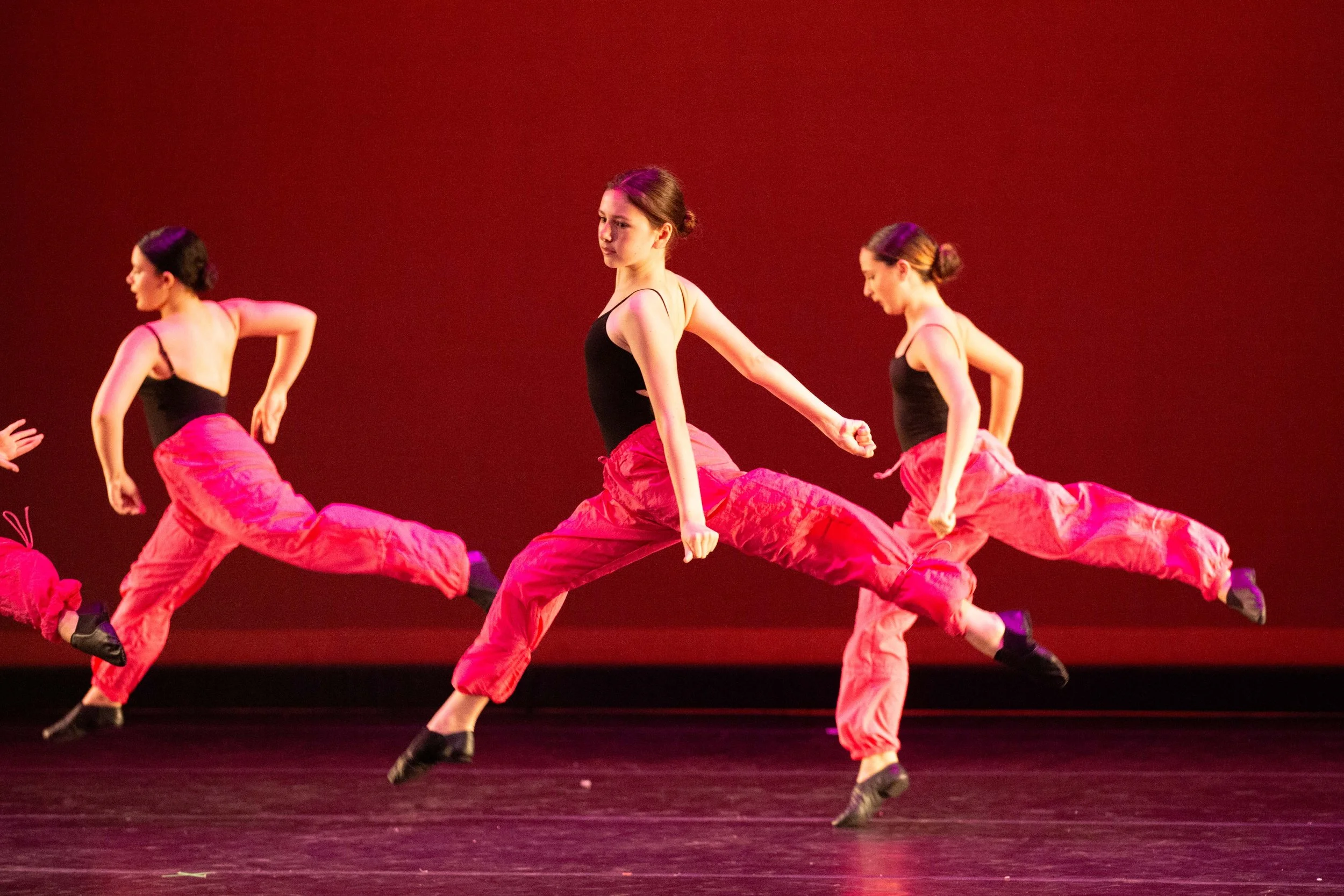 Dancers performing a jazz routine on stage.