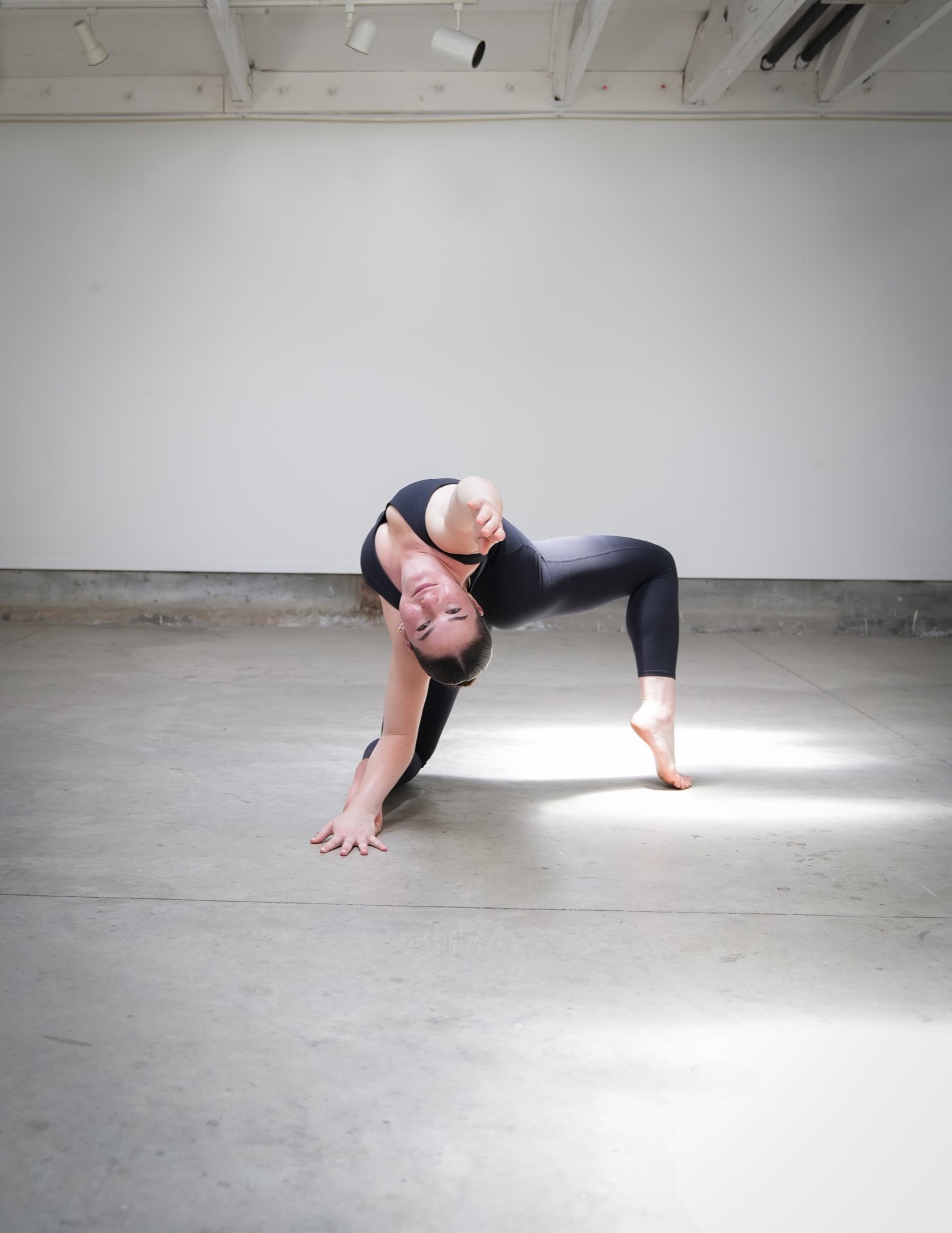 Dancer in a backbend, one leg extended, on the studio floor.