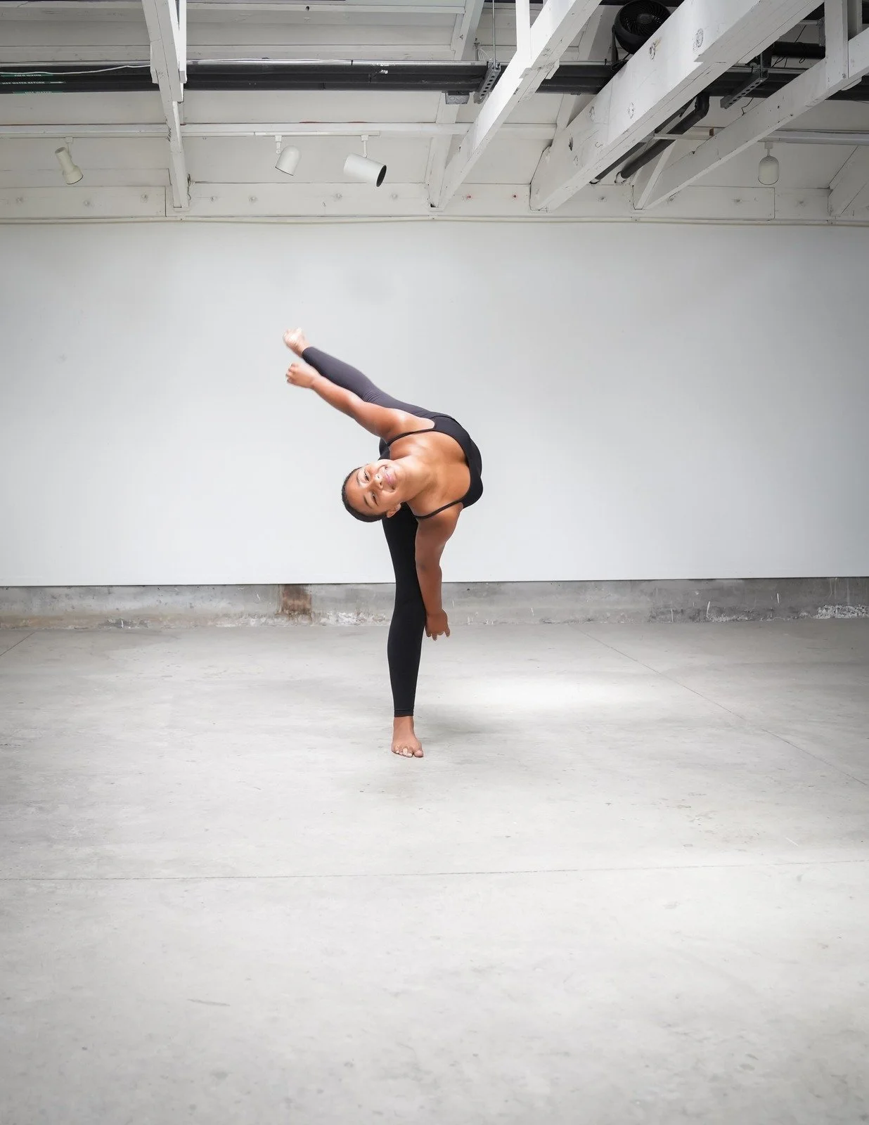 Dancer in a sideways bend, reaching toward the floor.
