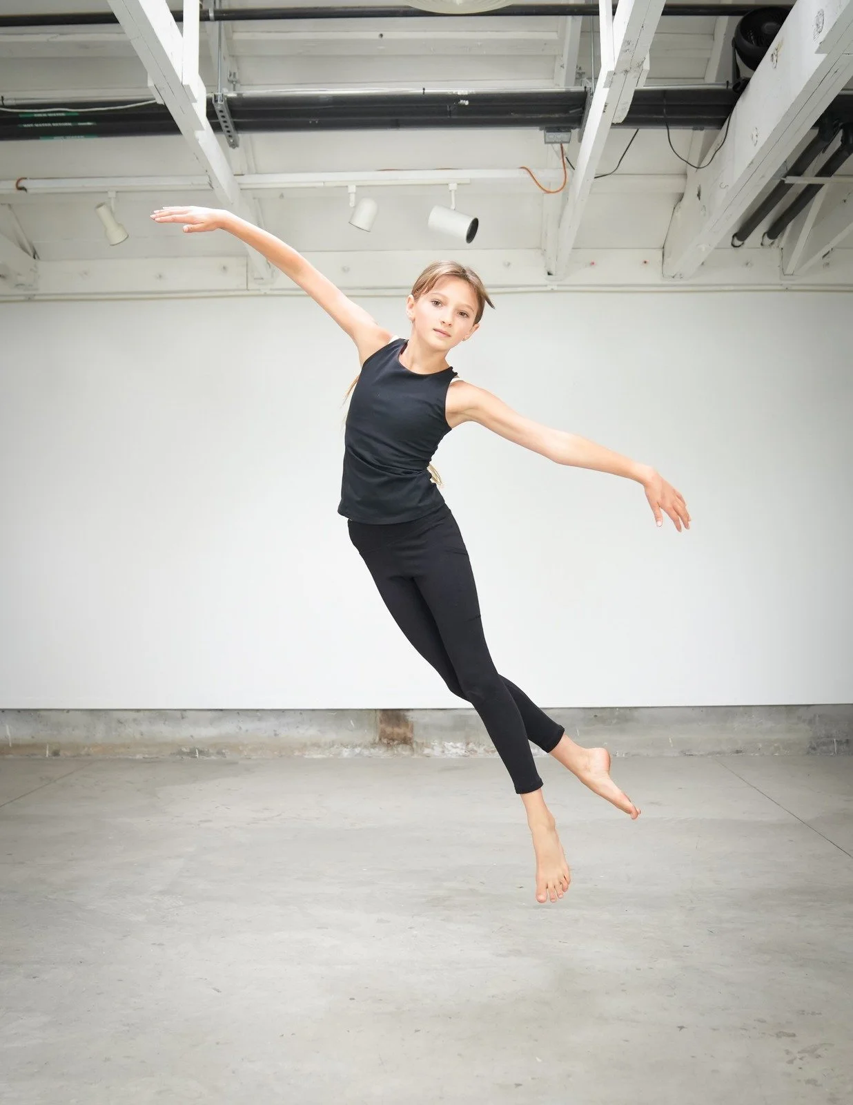 Dancer mid-air in a full split leap, arms wide.