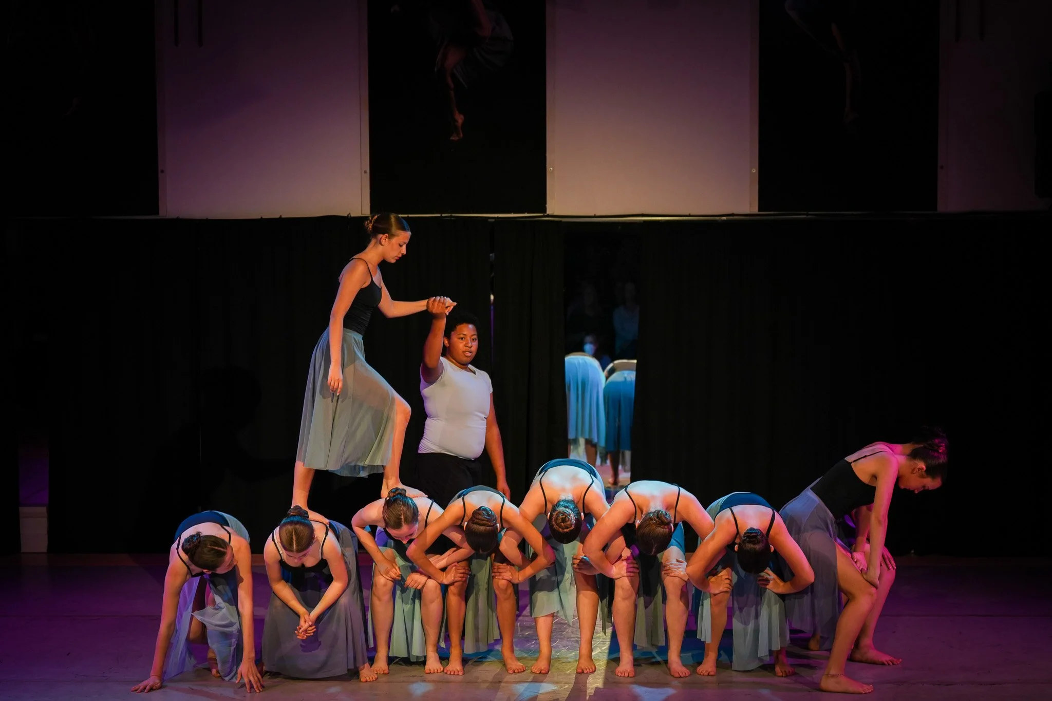 TWDCC company dancers forming a human bridge on stage.