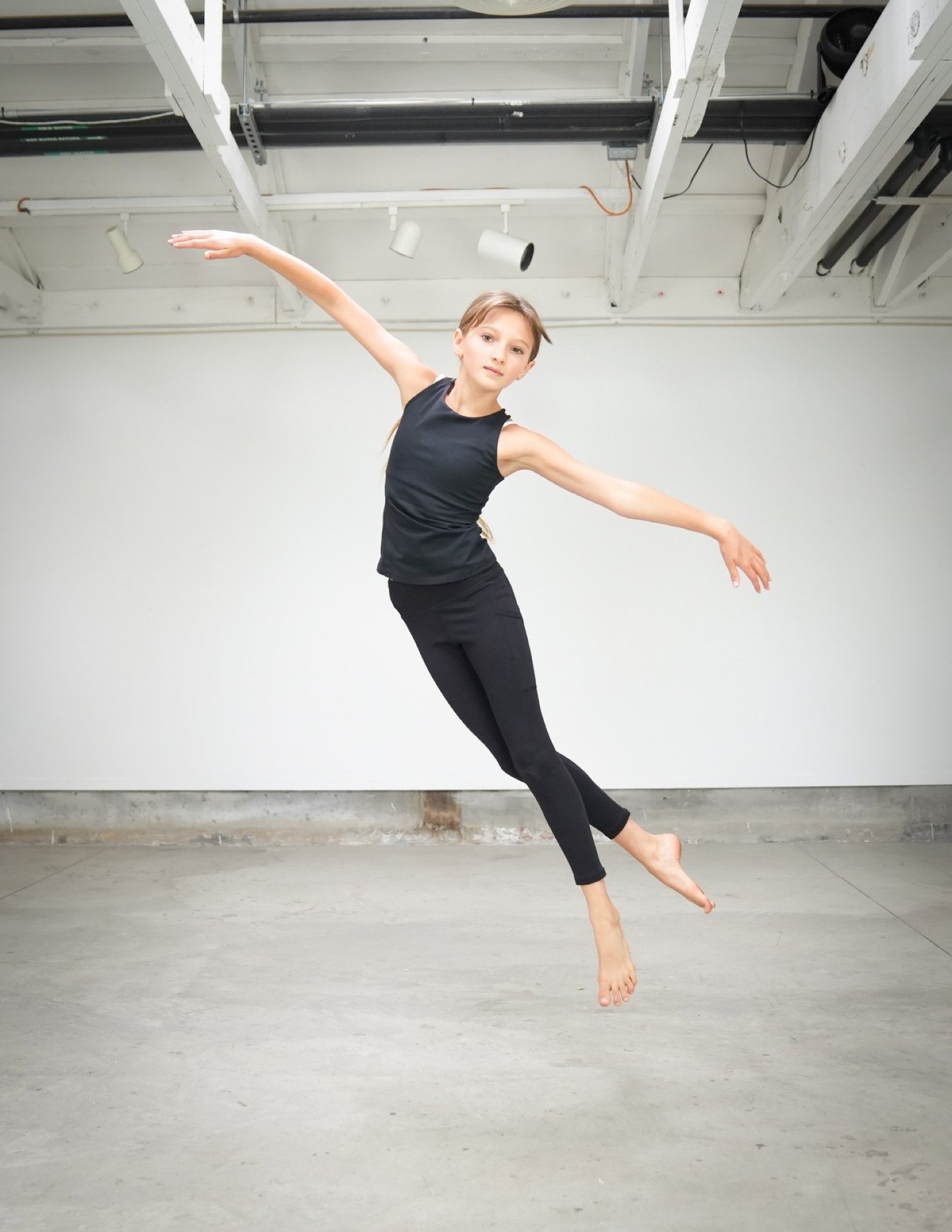 A young dancer mid-jump in TWDCC's light-filled studio.